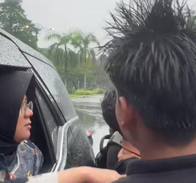 
					Bupati Siak, Afni Zulkifli, saat diminta pelajar berfoto di tengah hujan.