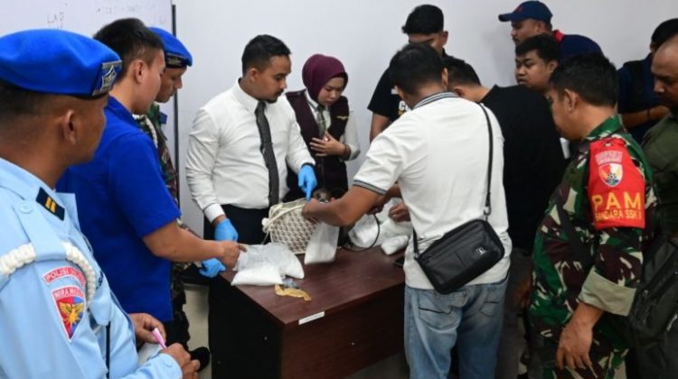 Petugas saat memeriksa koper tersangka. (Ist)