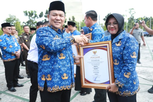 Bupati Siak Afni Zulkifli saat menerima penghargaan UHC dari Plt Gubernur Riau, SF. Hariyanto. F: Ist