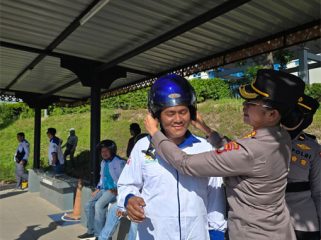 Kombes Pol. Dr. Nona Pricillia Ohei, S.I.K., S.H., M.H.,  memakai helm kepada salah seorang pengedara sepeda motor. (Foto: Humas Polda Kepri)