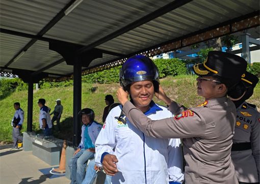 Kombes Pol. Dr. Nona Pricillia Ohei, S.I.K., S.H., M.H.,  memakai helm kepada salah seorang pengedara sepeda motor. (Foto: Humas Polda Kepri)